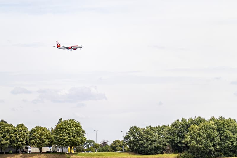 Beek, South Limburg / Netherlands. July 19, 2020. Plane flying over a parking lot for cargo trucks next to a highway and farmland