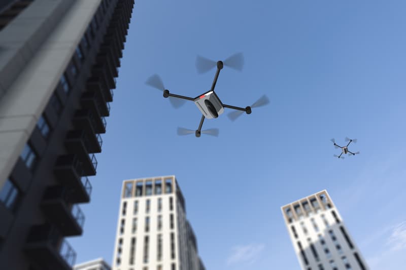 Drones flying over modern buildings in a city under clear blue sky